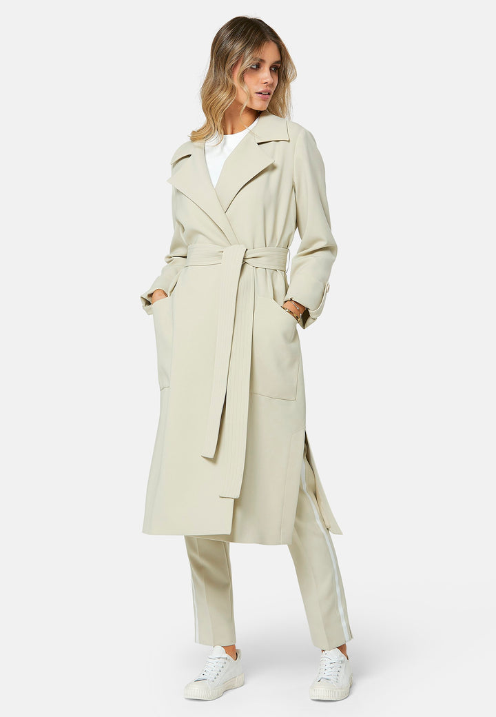 Lydiah captures the essence of sophisticated simplicity with its elegant design. This fluid trench coat features a neutral bone hue that radiates timeless appeal. It comes with a meticulously row-stitched, detachable belt that adds a touch of refinement, allowing you the flexibility to cinch it at the waist or wear it open for a relaxed look.