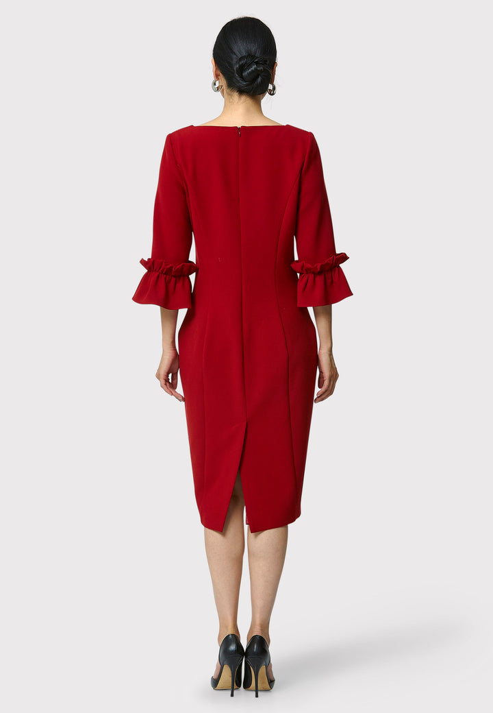 The Maisie Garnet Red Dress, impeccably tailored from signature tricotine fabric with a hint of stretch. This body-skimming silhouette features a round neck and bracelet-length sleeves complemented by exaggerated frill cuffs, ideal for evening cocktails, a night at the theatre, or a stylish winter wedding.