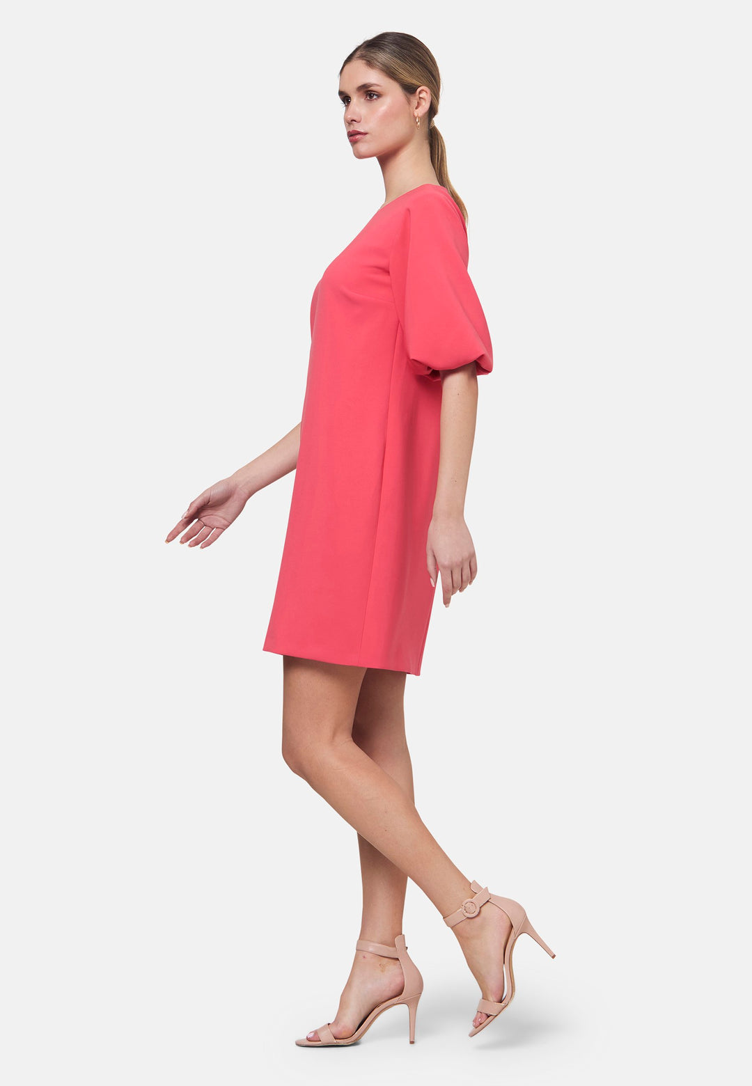 Mia, a chic short-shift dress in a fun watermelon pink hue. This feminine piece features a timeless silhouette with voluminous three-quarter puff sleeves and a round neckline. Its clean lines and relaxed fit make it ideal for both daytime outings and evening occasions.