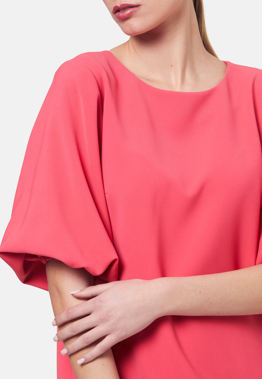 Mia, a chic short-shift dress in a fun watermelon pink hue. This feminine piece features a timeless silhouette with voluminous three-quarter puff sleeves and a round neckline. Its clean lines and relaxed fit make it ideal for both daytime outings and evening occasions.