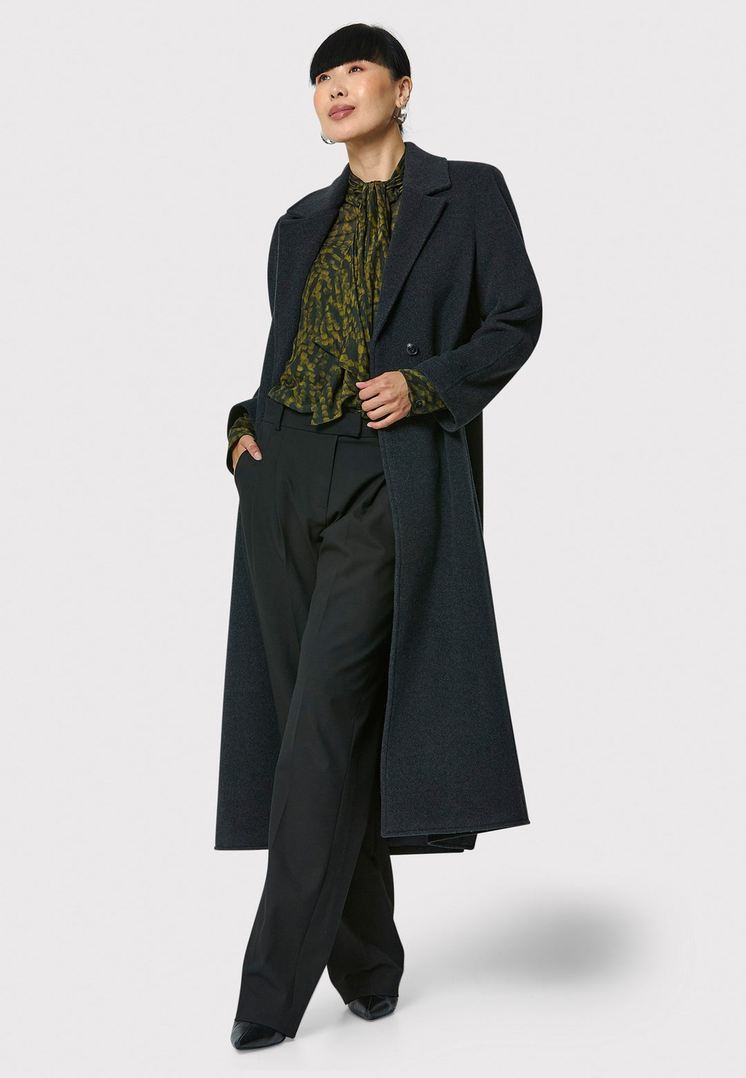 The Mikaela Charcoal Grey Coat, crafted from a luxurious blend of wool and cashmere, offers both style and versatility. This long duster coat features a classic collar and revere, button closure and practical side seam slits. Wear it straight for a relaxed silhouette, or cinch the waist with the matching self-fabric belt for a more defined shape. Complete with side seam pockets, this coat is a refined addition to your outerwear collection.