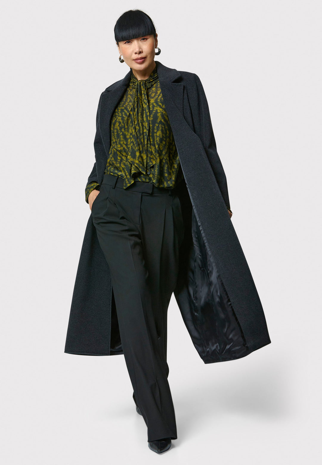 The Mikaela Charcoal Grey Coat, crafted from a luxurious blend of wool and cashmere, offers both style and versatility. This long duster coat features a classic collar and revere, button closure and practical side seam slits. Wear it straight for a relaxed silhouette, or cinch the waist with the matching self-fabric belt for a more defined shape. Complete with side seam pockets, this coat is a refined addition to your outerwear collection.