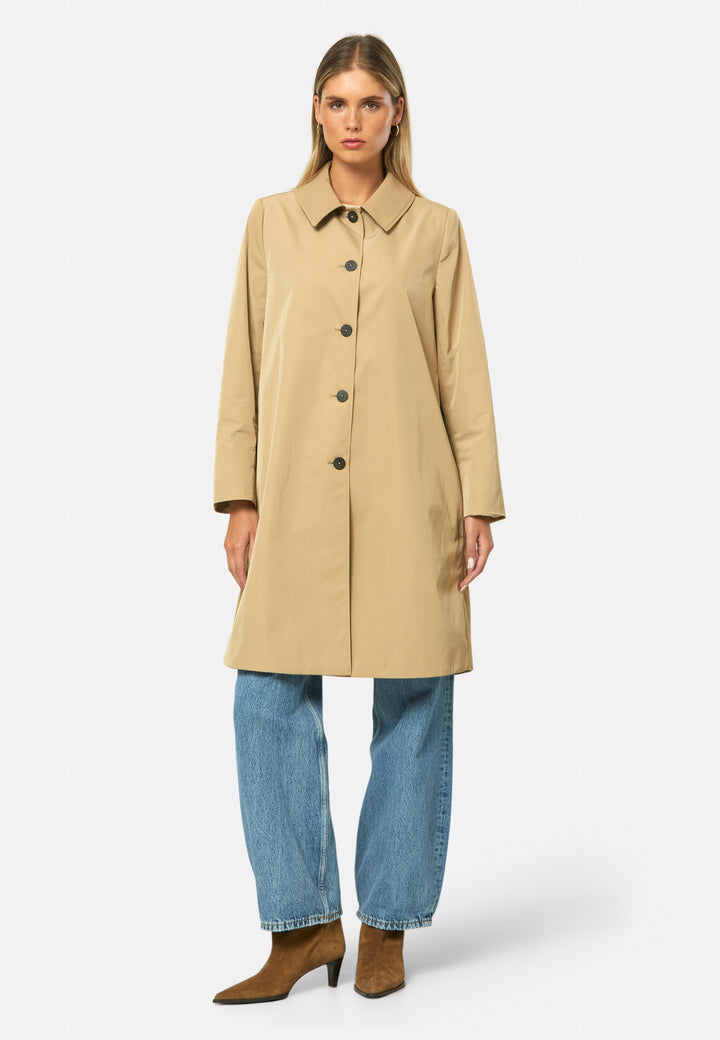 woman wearing beige mac trench coat over jeans