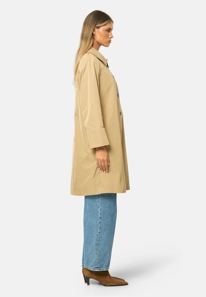 woman wearing beige mac trench coat over jeans