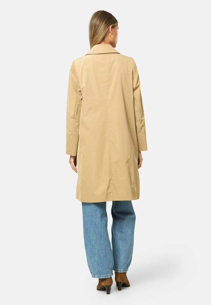 woman wearing beige mac trench coat over jeans