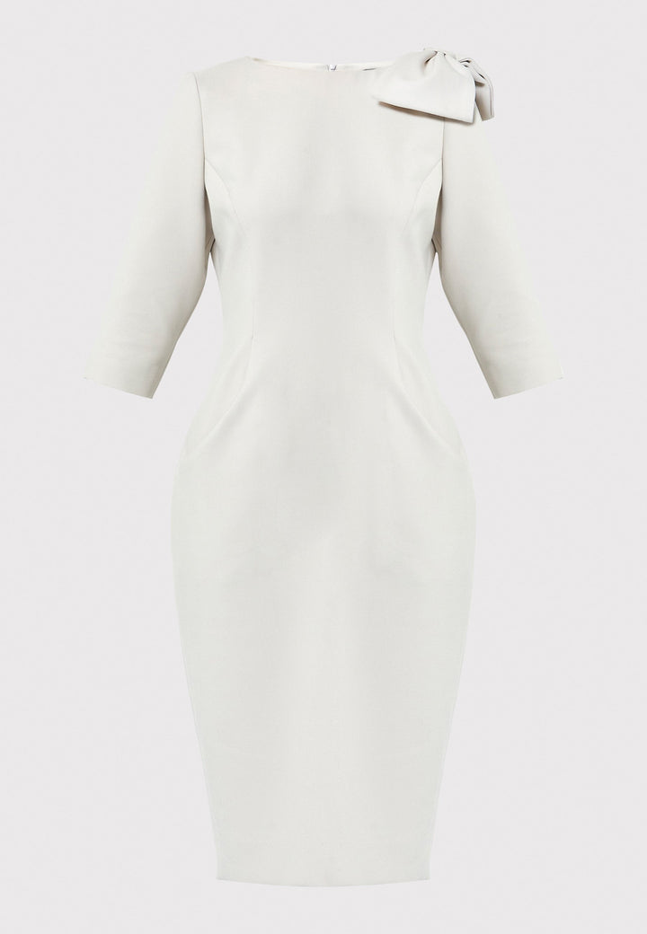 The Natalie dress, crafted from a stone hued tricotine fabric with a hint of stretch, this figure-hugging dress showcases a chic slash neckline, bow detailing, and a mid-calf pencil skirt. Suitable for a night out with friends, a romantic date, or a winter wedding.