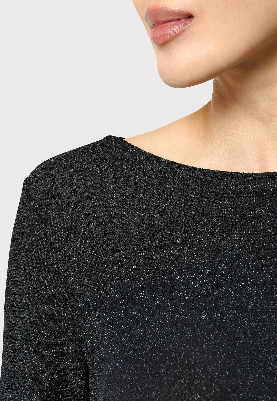 Introducing the Roxanne Black Shimmer Top, an updated version of the beloved best-selling faux-wrap top. This season's design features a beautifully draped neckline for an elegant touch. With its hip-length cut and full-length sleeves, this top combines comfort and chic style effortlessly. Crafted from a black sparkly jersey fabric, it adds a touch of glamour to any outfit. Embrace the ultimate in comfortable chic with the Roxanne Black Shimmer Top.