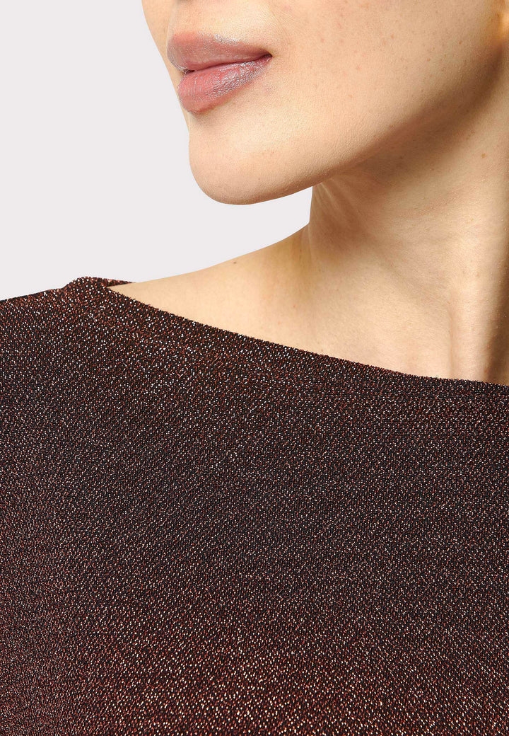 Introducing the Roxanne Copper Shimmer Top, an updated version of the beloved best-selling faux-wrap top. This season's design features a beautifully draped neckline for an elegant touch. With its hip-length cut and full-length sleeves, this top combines comfort and chic style effortlessly. Crafted from a black sparkly jersey fabric, it adds a touch of glamour to any outfit. Embrace the ultimate in comfortable chic with the Roxanne Copper Shimmer Top.