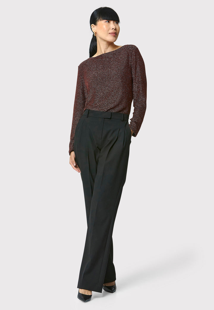 Introducing the Roxanne Copper Shimmer Top, an updated version of the beloved best-selling faux-wrap top. This season's design features a beautifully draped neckline for an elegant touch. With its hip-length cut and full-length sleeves, this top combines comfort and chic style effortlessly. Crafted from a black sparkly jersey fabric, it adds a touch of glamour to any outfit. Embrace the ultimate in comfortable chic with the Roxanne Copper Shimmer Top.