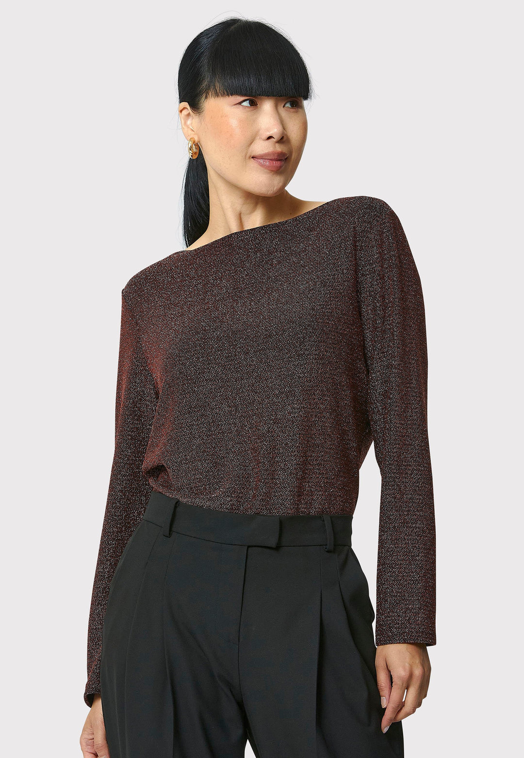 Introducing the Roxanne Copper Shimmer Top, an updated version of the beloved best-selling faux-wrap top. This season's design features a beautifully draped neckline for an elegant touch. With its hip-length cut and full-length sleeves, this top combines comfort and chic style effortlessly. Crafted from a black sparkly jersey fabric, it adds a touch of glamour to any outfit. Embrace the ultimate in comfortable chic with the Roxanne Copper Shimmer Top.