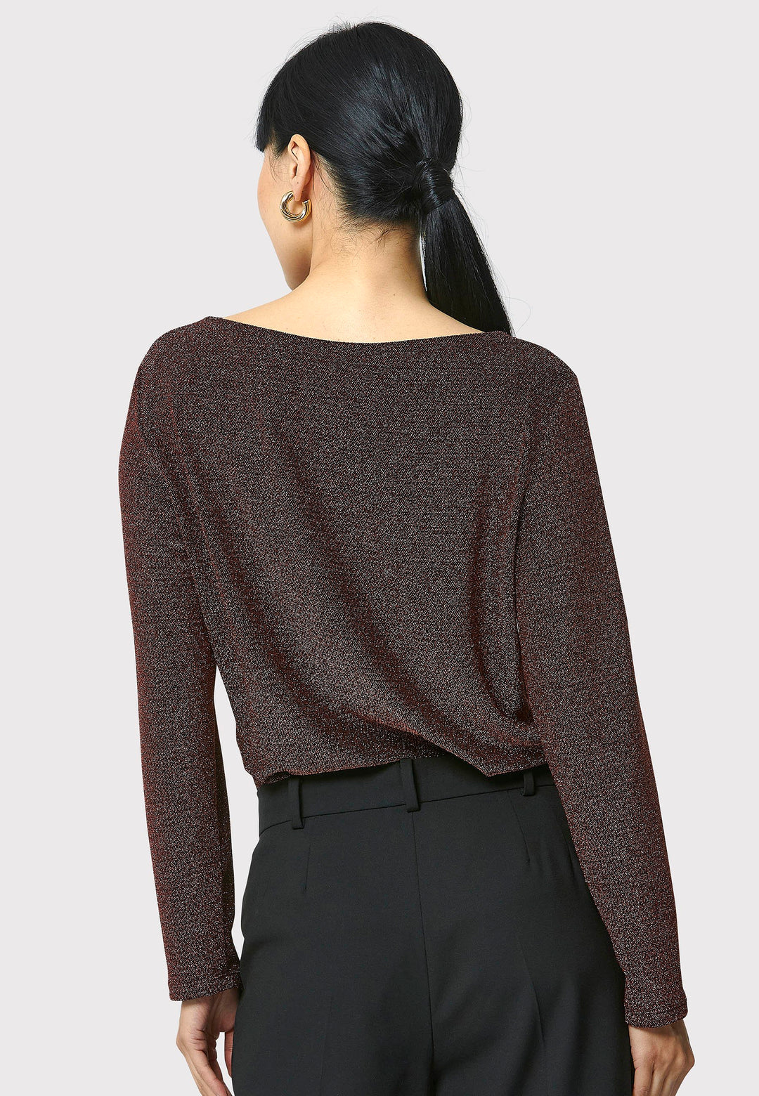 Introducing the Roxanne Copper Shimmer Top, an updated version of the beloved best-selling faux-wrap top. This season's design features a beautifully draped neckline for an elegant touch. With its hip-length cut and full-length sleeves, this top combines comfort and chic style effortlessly. Crafted from a black sparkly jersey fabric, it adds a touch of glamour to any outfit. Embrace the ultimate in comfortable chic with the Roxanne Copper Shimmer Top.