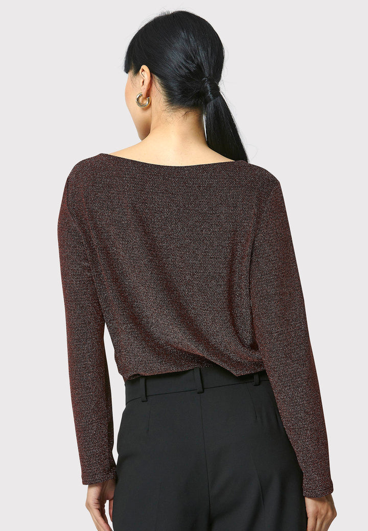 Introducing the Roxanne Copper Shimmer Top, an updated version of the beloved best-selling faux-wrap top. This season's design features a beautifully draped neckline for an elegant touch. With its hip-length cut and full-length sleeves, this top combines comfort and chic style effortlessly. Crafted from a black sparkly jersey fabric, it adds a touch of glamour to any outfit. Embrace the ultimate in comfortable chic with the Roxanne Copper Shimmer Top.
