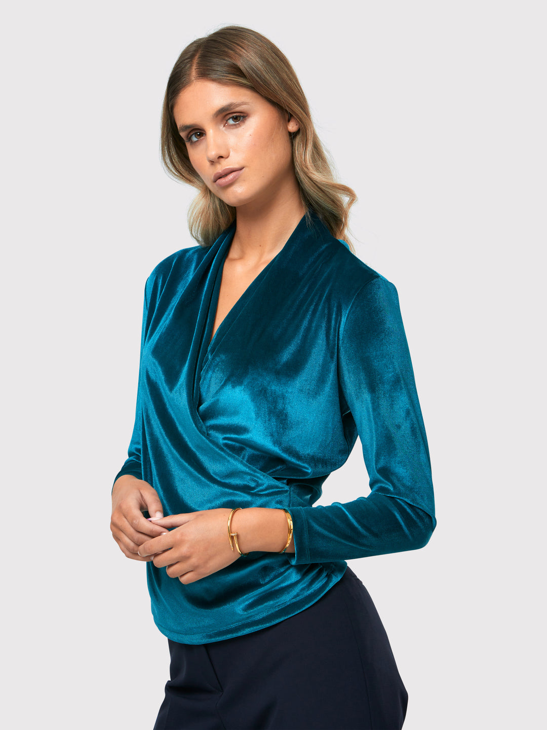 Introducing the Roxanne Petrol Top, an updated version of the beloved best-selling faux-wrap top. This stunning top showcases a sleek silhouette with a gracefully draped v-neckline, creating an air of elegance. Crafted from luxurious stretch velvet in a rich teal tone, it emanates sophistication and allure. The hip-length cut and full-length sleeves offer both comfort and style. Elevate your fashion game with the Roxanne Petrol Top, the epitome of refined chic and a statement piece for any occasion.