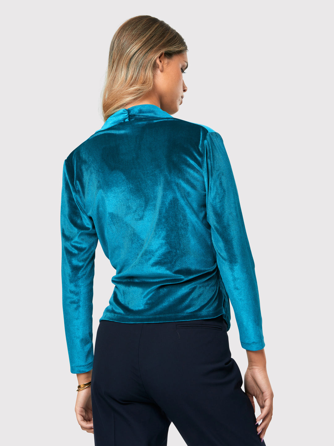 Introducing the Roxanne Petrol Top, an updated version of the beloved best-selling faux-wrap top. This stunning top showcases a sleek silhouette with a gracefully draped v-neckline, creating an air of elegance. Crafted from luxurious stretch velvet in a rich teal tone, it emanates sophistication and allure. The hip-length cut and full-length sleeves offer both comfort and style. Elevate your fashion game with the Roxanne Petrol Top, the epitome of refined chic and a statement piece for any occasion.