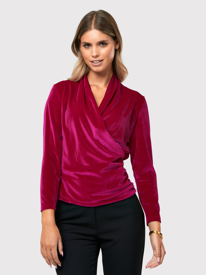 Introducing the Roxanne Fuchsia Velvet Top, an updated version of the beloved best-selling faux-wrap top. This captivating top boasts a sleek silhouette and a beautifully draped v-neckline, adding an elegant touch to your ensemble. Crafted from luxurious fuchsia stretch velvet, it radiates opulence and allure. With its hip-length cut and full-length sleeves, this top effortlessly combines comfort and style.