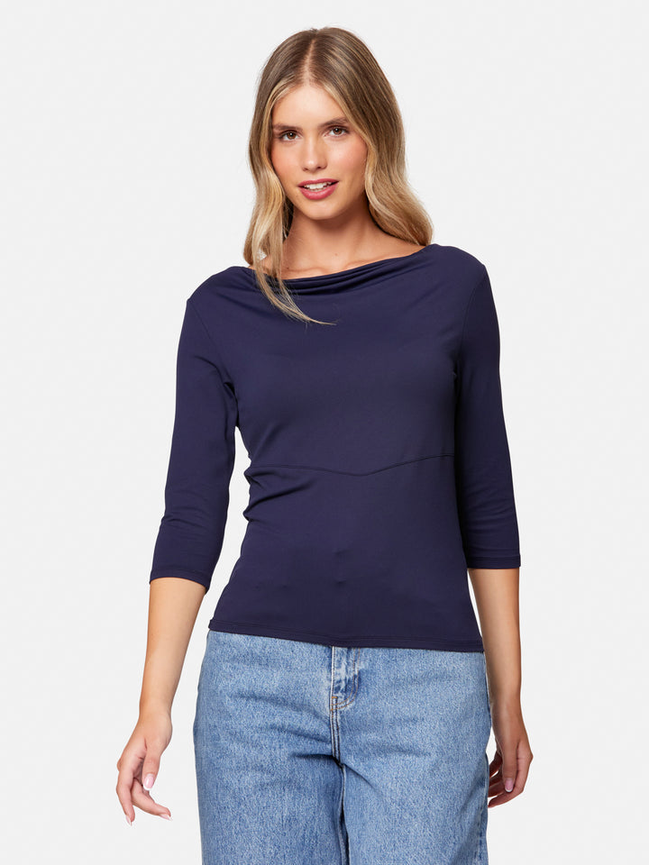 Woman wearing a navy blue long-sleeve top and light blue jeans on a white background