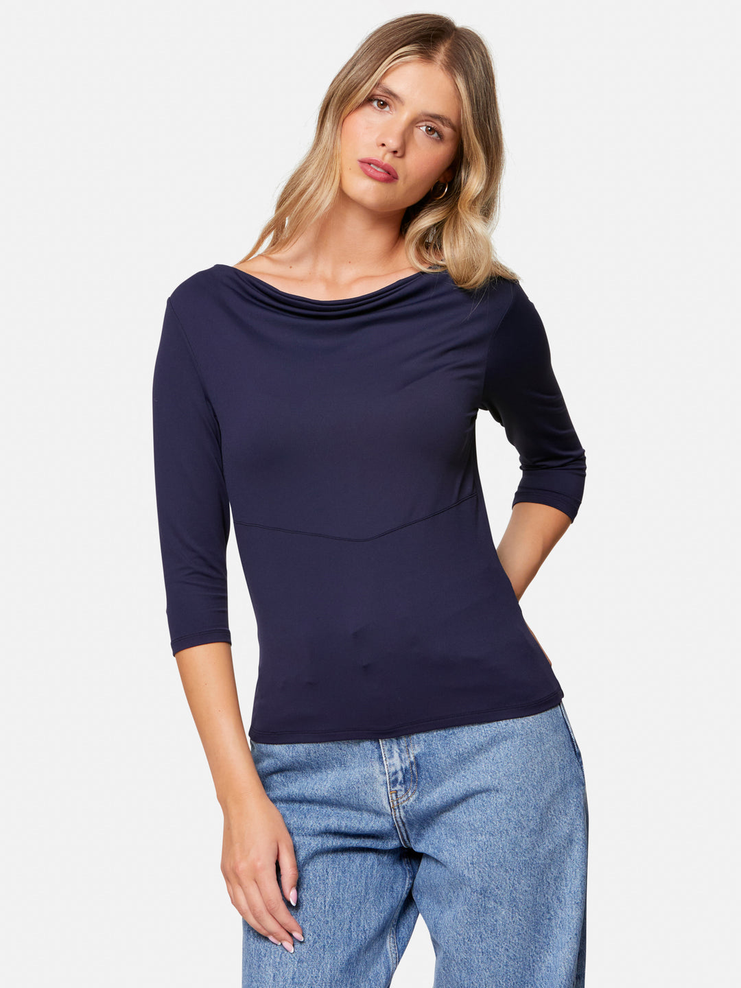 Woman wearing a navy blue top and blue jeans on a white background