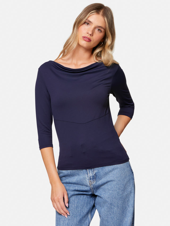 Woman wearing a navy blue top and blue jeans on a white background