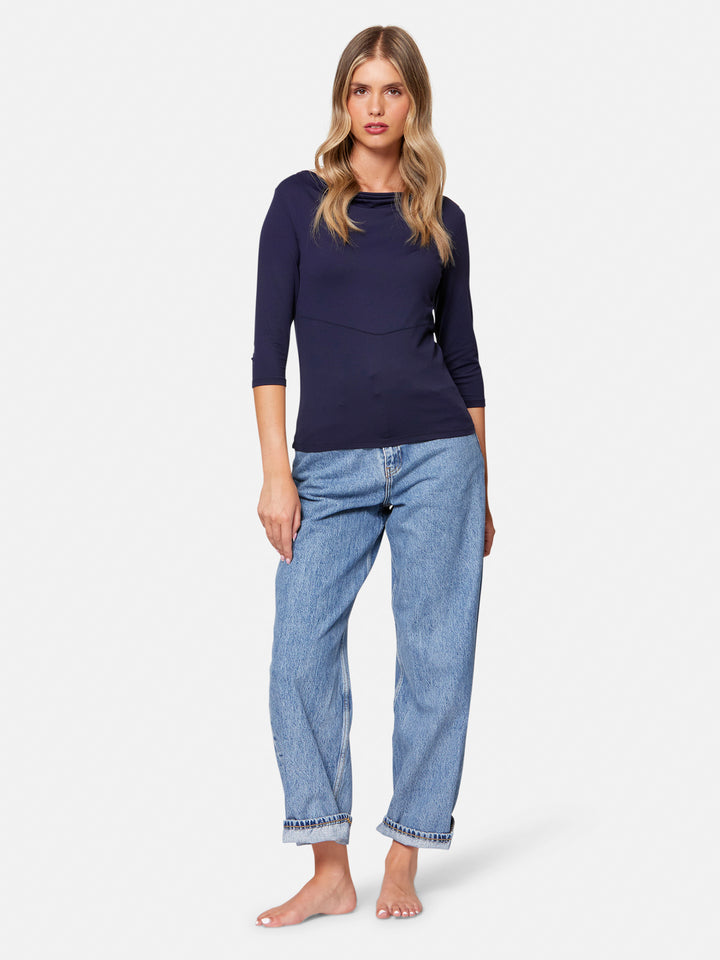 Woman wearing a navy long-sleeve top and light blue jeans on a white background