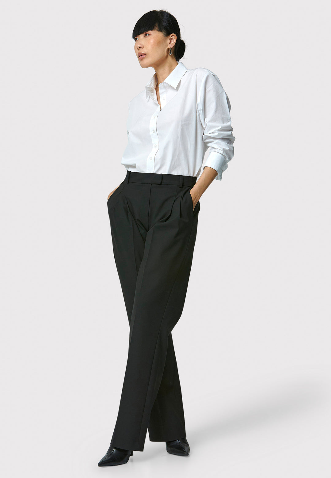 Person wearing a white shirt and black pants on a white background