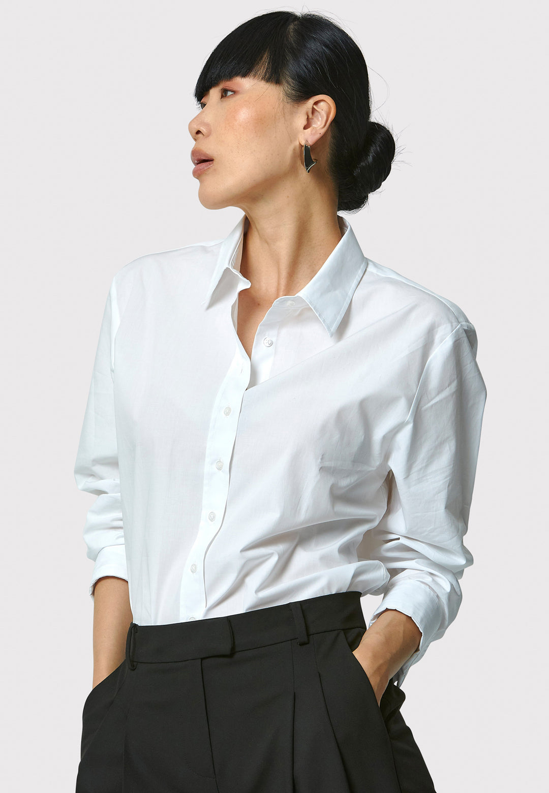 Person wearing a white shirt and black pants against a plain background