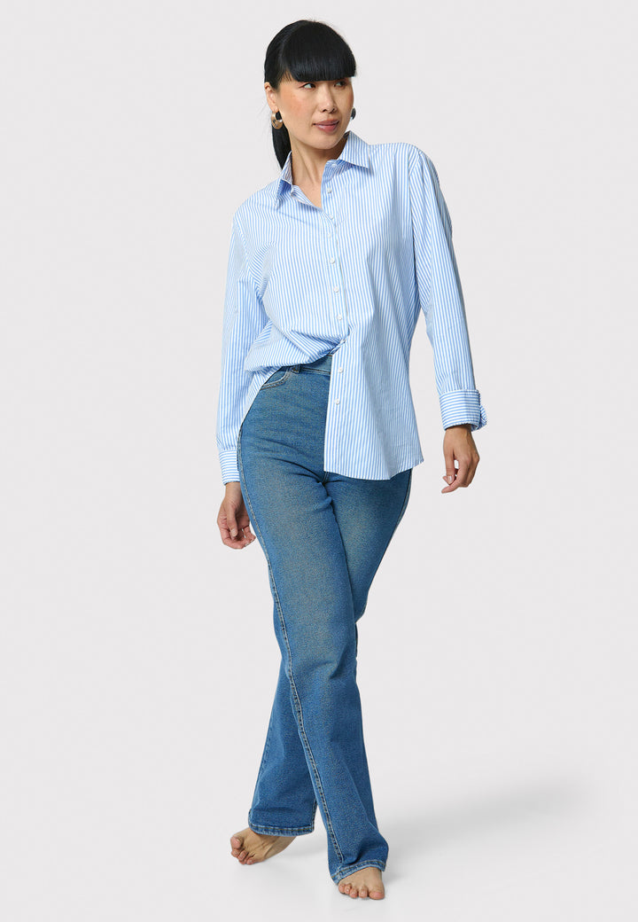 Woman wearing a light blue striped shirt and blue jeans on a white background