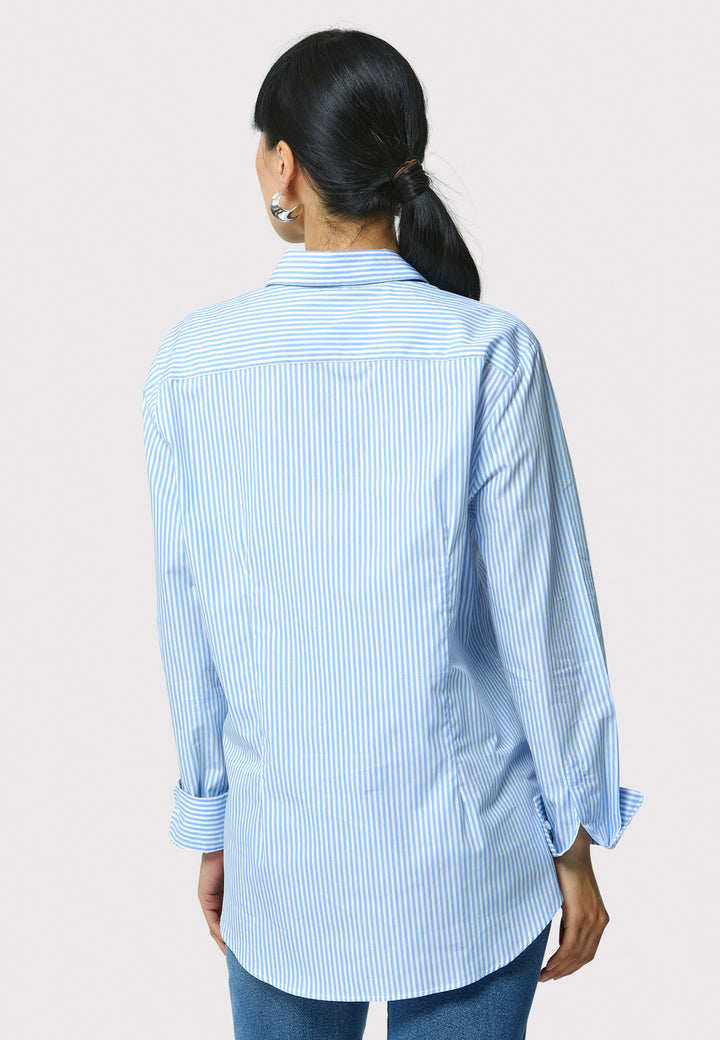 Woman wearing a light blue and white striped shirt against a plain background