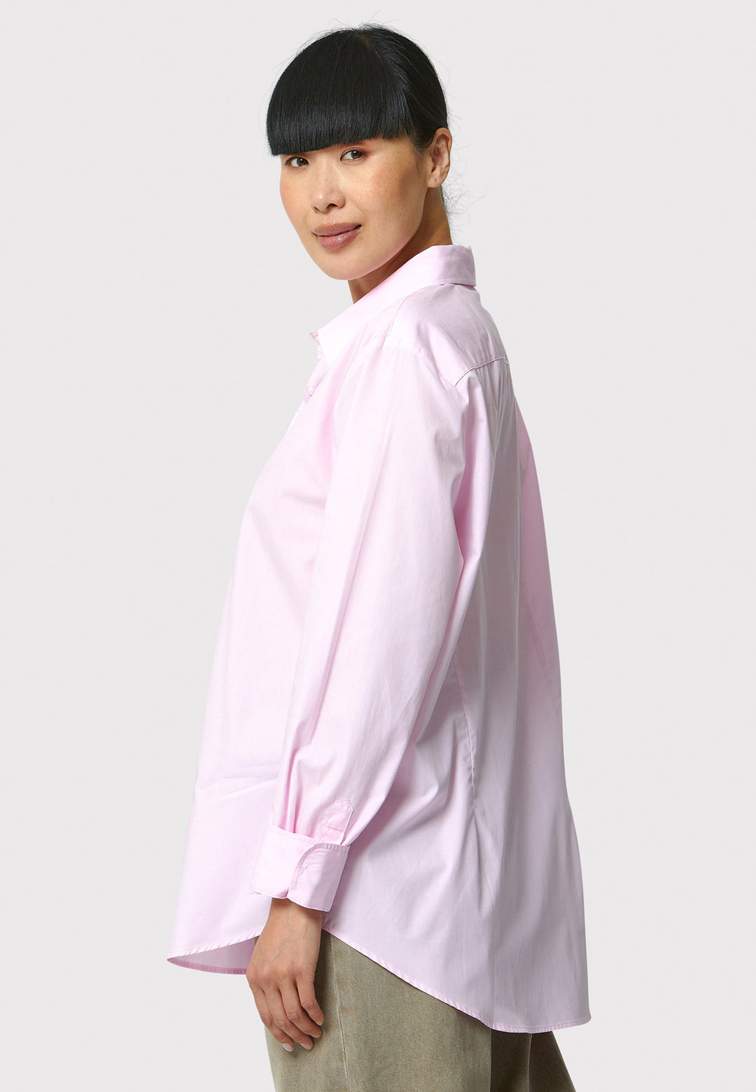 Person wearing a light pink shirt on a plain background