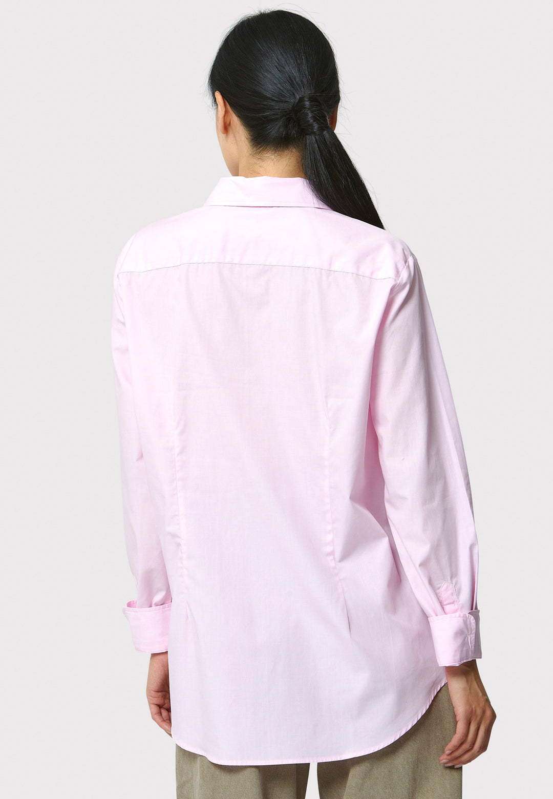 Person wearing a light pink shirt on a plain background