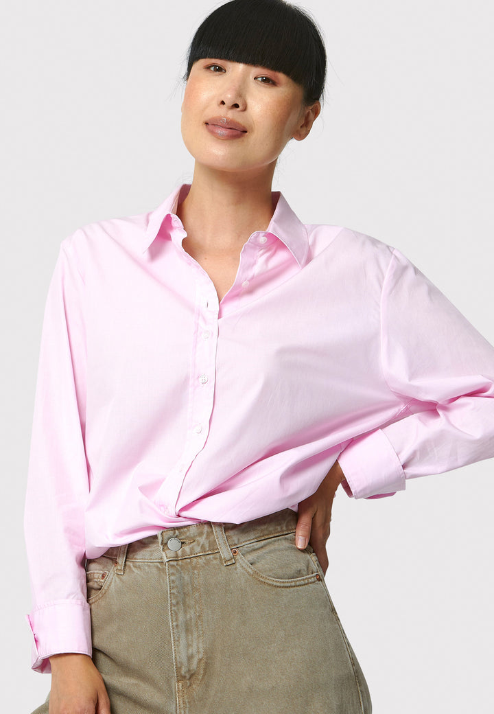 Person wearing a light pink shirt and beige pants on a white background
