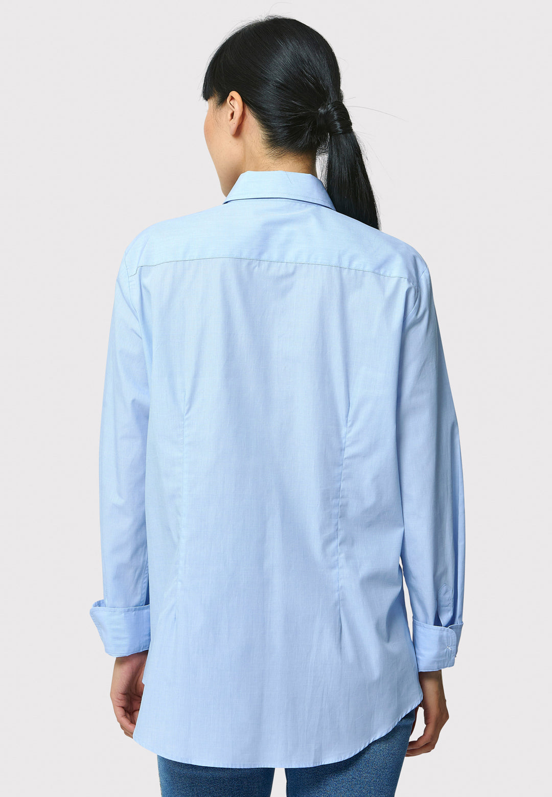 Person wearing a light blue shirt on a plain background