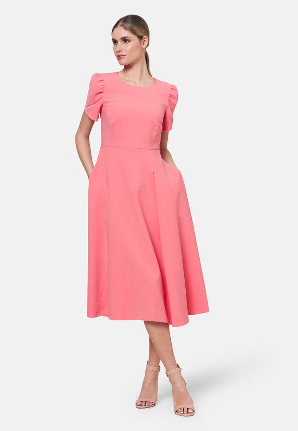 The Vera Poney Pink Dress is perfect for special occasions. It features a flattering fit-and-flare silhouette and short gathered sleeves with an elegant overlapping detail. The mid-calf length skirt flares out gracefully, adding elegance to the dress. Crafted from a comfortable fabric blend, it ensures ease of movement and a polished look.