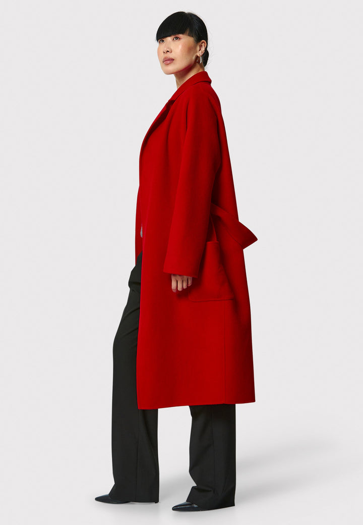 Introducing the Zola Cherry Red Cashmere Coat, a luxurious blend of cashmere and wool. This unlined coat features an oversized silhouette with patch pockets and a detachable belt. The dropped sleeves and tailor pick stitch finish add a touch of sophistication. Complete with a traditional collar and revere, it's a statement piece for your winter wardrobe.