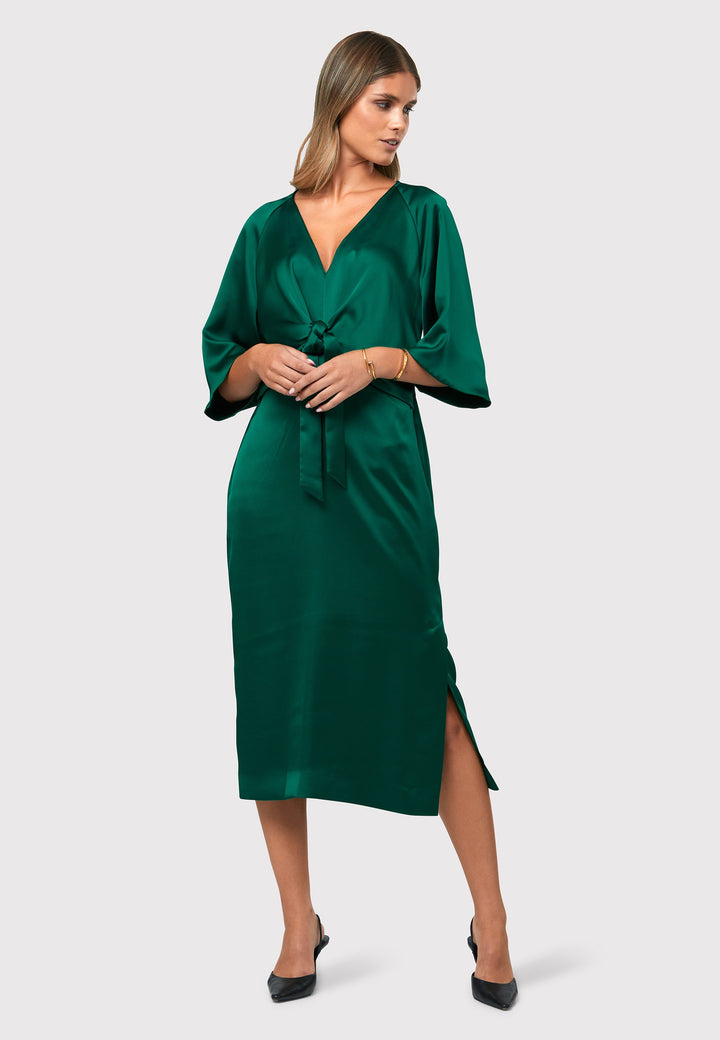 Unleash your inner Goddess with the Ailbhe dress, a vision of elegance and grace. This dress boasts an exquisitely draped silhouette, crafted from a luxurious dark emerald green satin that flows like liquid. The flattering front ties elevate the easy-fit V-neck dress, adding a touch of sophistication. Convenient side seam pockets offer practicality without compromising style. 