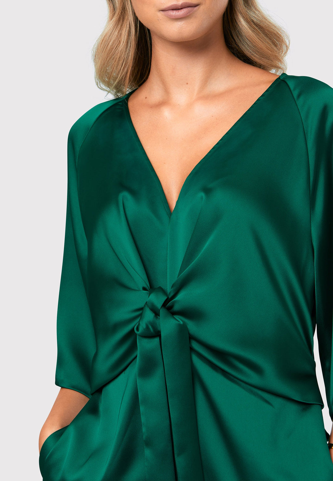 Unleash your inner Goddess with the Ailbhe dress, a vision of elegance and grace. This dress boasts an exquisitely draped silhouette, crafted from a luxurious dark emerald green satin that flows like liquid. The flattering front ties elevate the easy-fit V-neck dress, adding a touch of sophistication. Convenient side seam pockets offer practicality without compromising style. 