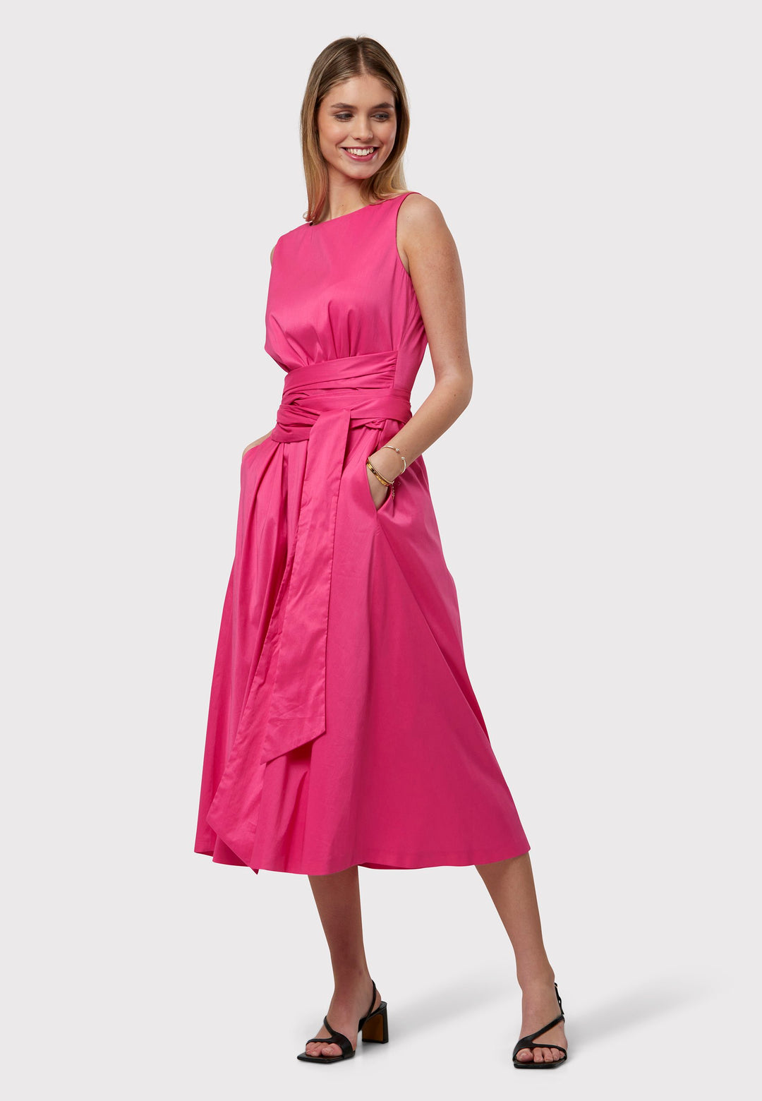 Our best-selling Avril dress returns in bright pink. Elevate your summer look with an easy-fitting dress. A sleeveless silhouette featuring a defined waist and an oversized wrap tie. The flared skirt falls to the mid-calf with side seam pockets.