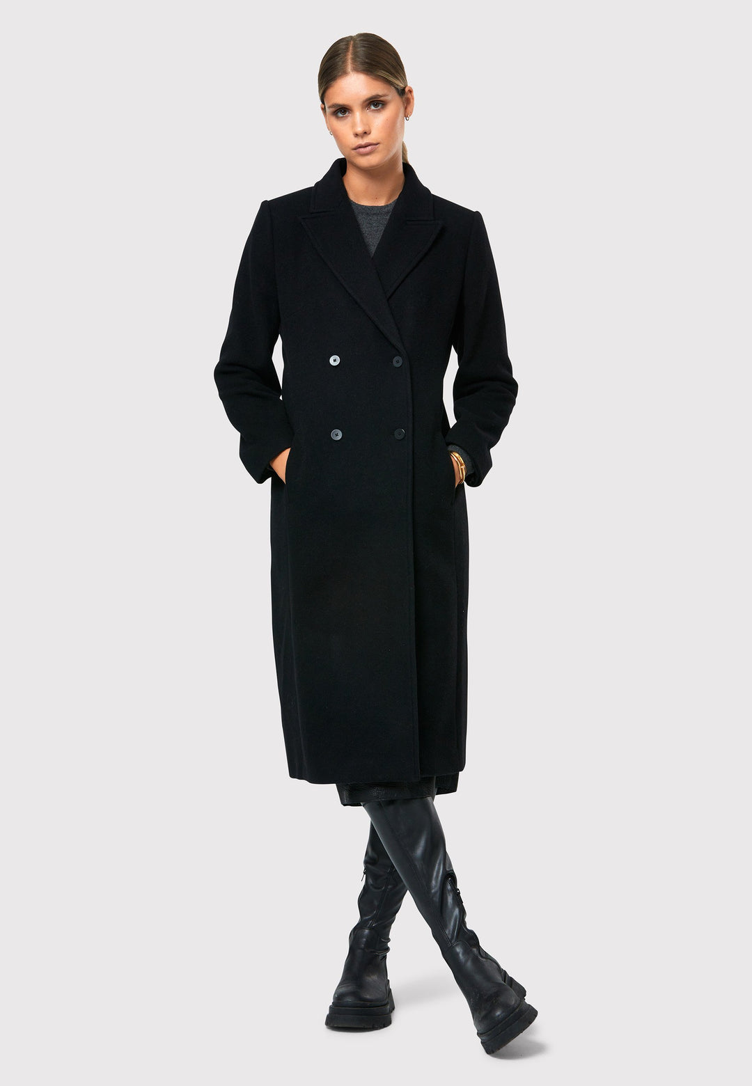 Introducing the Beryl Black Coat, your ultimate companion for warmth and style this winter season. This exquisite coat features a classic double-breasted silhouette with a four-button fastening and a sleek collar and revere detail, inspired by men's tailoring. Crafted from a cozy melton fabric, it falls below the knee, enveloping you in both comfort and sophistication. Stay fashionable and cozy with the Beryl Black Coat, a must-have addition to your winter wardrobe.
