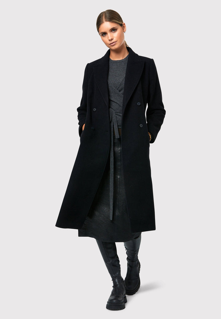 Introducing the Beryl Black Coat, your ultimate companion for warmth and style this winter season. This exquisite coat features a classic double-breasted silhouette with a four-button fastening and a sleek collar and revere detail, inspired by men's tailoring. Crafted from a cozy melton fabric, it falls below the knee, enveloping you in both comfort and sophistication. Stay fashionable and cozy with the Beryl Black Coat, a must-have addition to your winter wardrobe.