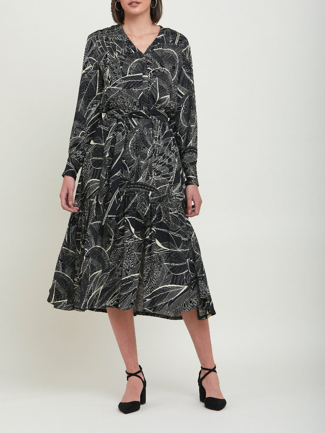 Beverly, an everyday dress. Crafted in a fluid, cream on black, botanical print viscose. A simple style with a V-neck button down bodice, handy pockets, elasticated waist & matching belt. Dress offers voluminous sleeves & a centre front slit on a fluid tiered skirt which falls to the mid-calf. 