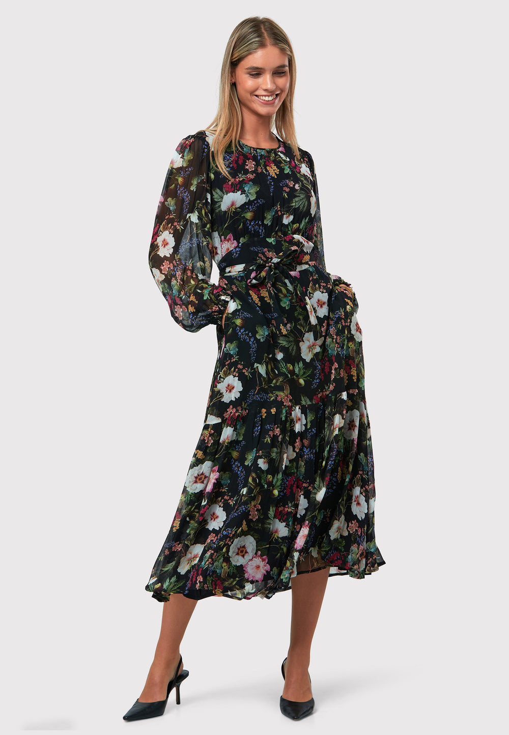 Bev Floral Noir Print Dress, a sophisticated choice that adds an elegant touch to your everyday wardrobe, now and in the future. This exquisite dress features a sweeping midi-length silhouette, designed with a blend of simplicity and feminine flair. The Jewel neckline is delicately enhanced with gentle gathers, while the softly flared skirt offers a flattering fit. 
