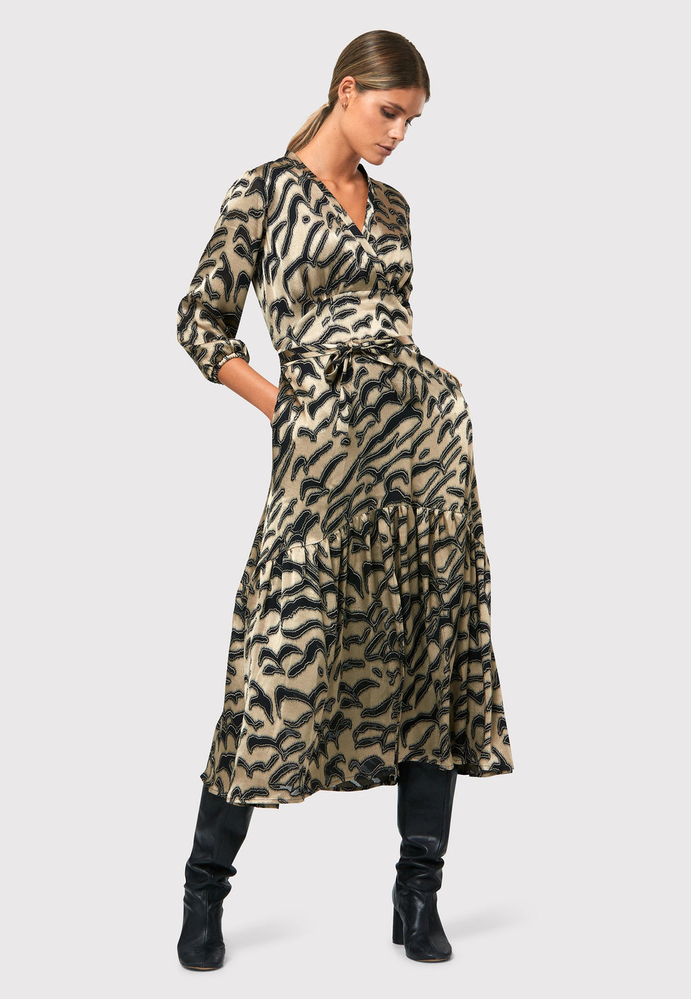 Elevate your wardrobe with the Beverly Devore dress in a captivating gold satin fabric adorned with black abstract details, creating a visually striking design, ensuring timeless elegance this season and beyond. Crafted in a sweeping midi silhouette, this dress embraces simplicity with a fit and flare skirt. The design features an elegant cross over V-neckline, adding a touch of sophistication. 