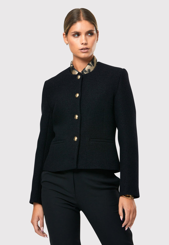 Introducing the Cassandra Black Jacket, a sleek and fitted piece crafted from a textured black boucle fabric. With its softly tailored silhouette, this jacket exudes modern elegance. The gold detail buttons add a touch of sophistication and elevate the overall aesthetic. Pair it effortlessly with the classic Jill pant for a timeless ensemble. The contemporary silhouette of the Cassandra Black Jacket is destined to become your go-to workwear icon for the season.