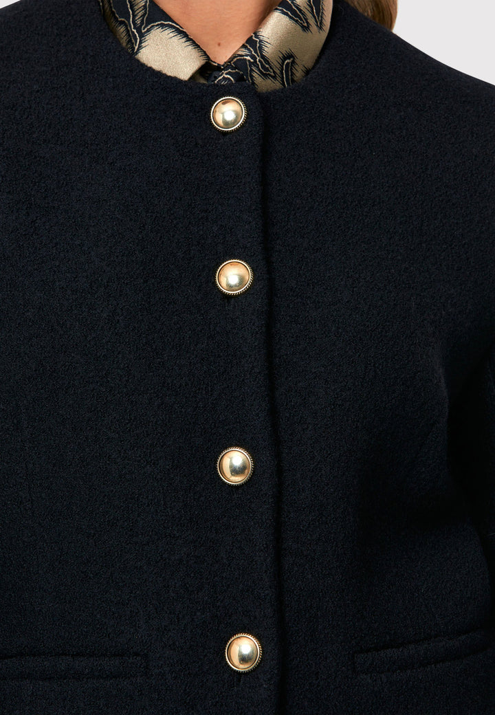 Introducing the Cassandra Black Jacket, a sleek and fitted piece crafted from a textured black boucle fabric. With its softly tailored silhouette, this jacket exudes modern elegance. The gold detail buttons add a touch of sophistication and elevate the overall aesthetic. Pair it effortlessly with the classic Jill pant for a timeless ensemble. The contemporary silhouette of the Cassandra Black Jacket is destined to become your go-to workwear icon for the season.