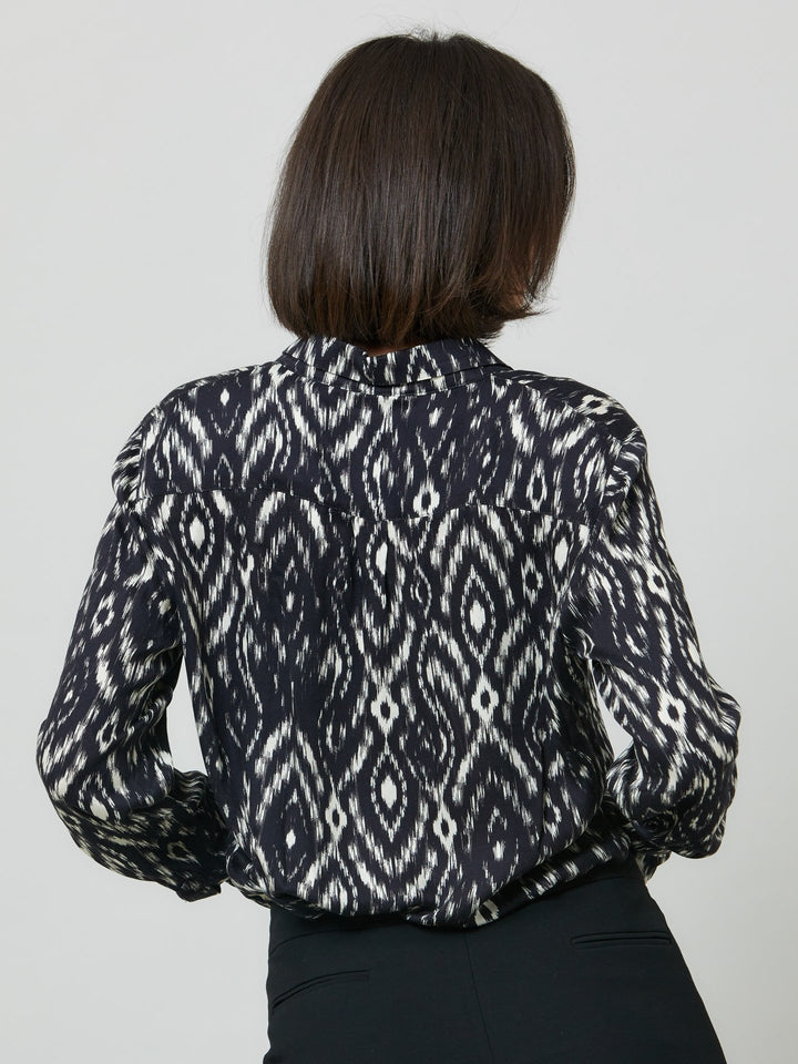 Ella, a classic utilitarian shirt crafted in a fluid black and cream ikat printed viscose. This must-have shirt features patch pockets, back yoke & center back box pleat. an easy-fit shirt to elevate your everyday. Helen's tip - style with the jill black pant for a sense of put-together ease.