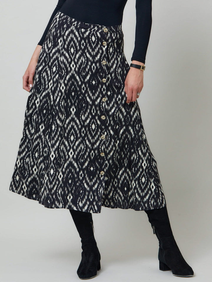 Meet saddie, the essential transeasonal skirt. Crafted in a fluid black and cream ikat printed viscose.. Off centered button through a-line silhouette with an elasticated back waist band. Relaxed elegance for everyday life. Style with our black timeless tops or dress it down with the khloe oatmeal sweatshirt.