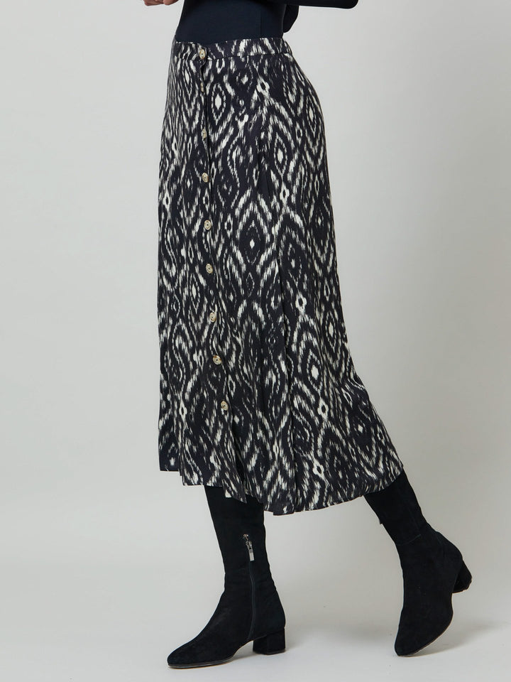 Meet saddie, the essential transeasonal skirt. Crafted in a fluid black and cream ikat printed viscose.. Off centered button through a-line silhouette with an elasticated back waist band. Relaxed elegance for everyday life. Style with our black timeless tops or dress it down with the khloe oatmeal sweatshirt.