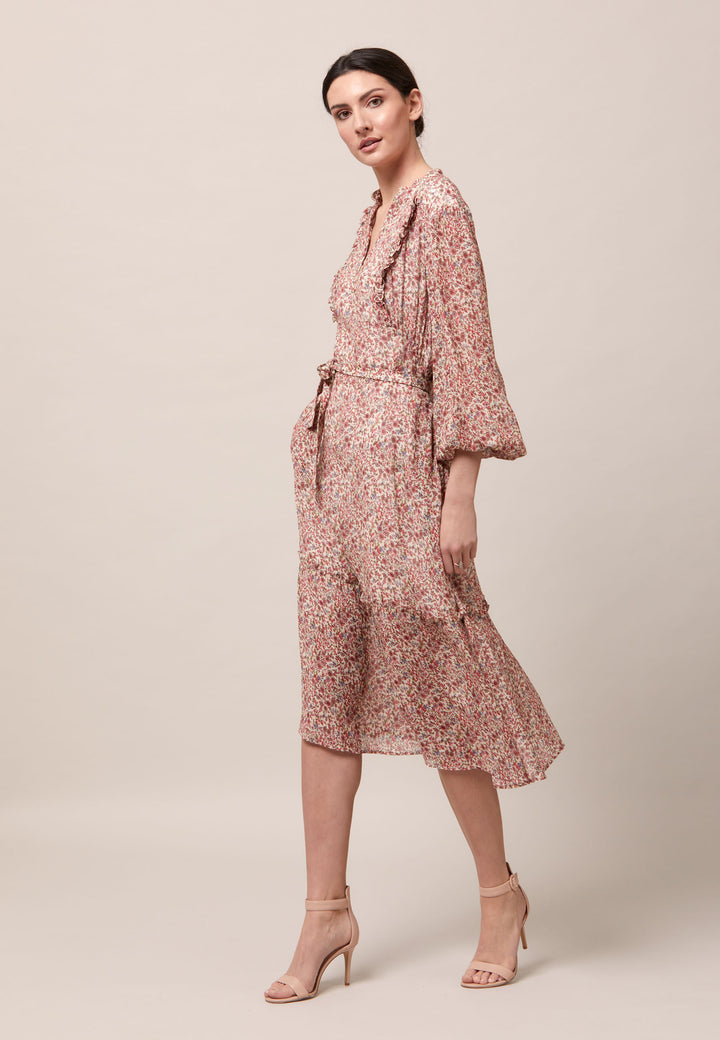 Bailey, femininity is having a moment. This flattering fit and flare silhouette offers a v-neckline with a frill embellished bodice. Waist is accentuated with a soft belt around the midriff for a customisable look that cinches the profile. The belt can be tied in the front or the back, adding versatility to this style. The voluminous semi-sheer sleeves subtly balance the classic design, finished with an elasticated cuff.