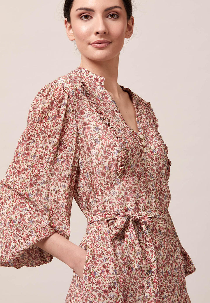 Bailey, femininity is having a moment. This flattering fit and flare silhouette offers a v-neckline with a frill embellished bodice. Waist is accentuated with a soft belt around the midriff for a customisable look that cinches the profile. The belt can be tied in the front or the back, adding versatility to this style. The voluminous semi-sheer sleeves subtly balance the classic design, finished with an elasticated cuff.