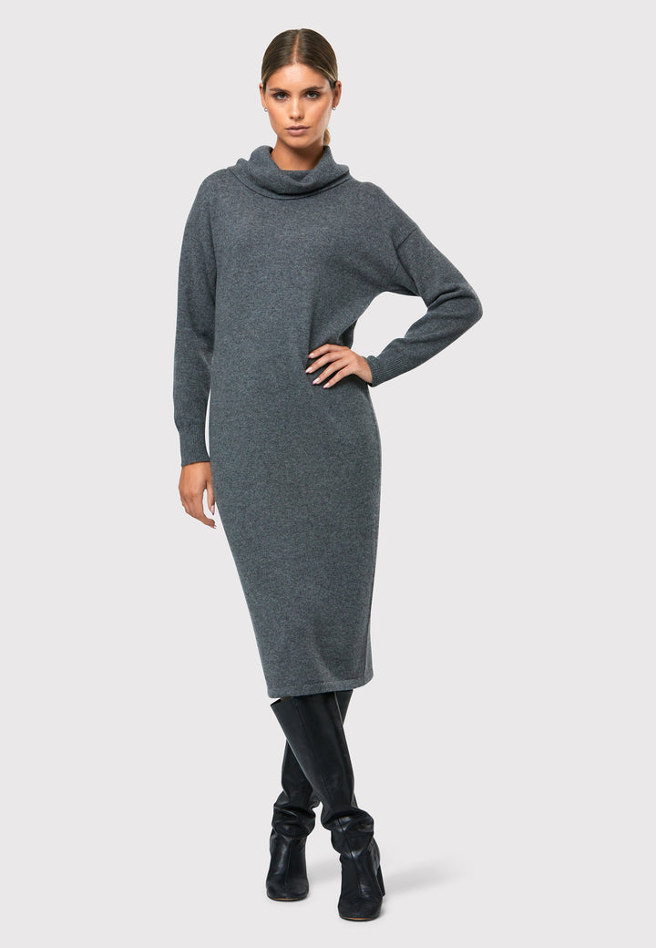 Have you met the Elora Camel Cashmere Dress? A chic and versatile addition to your wardrobe. This midi-length dress features a loose and drapey polo neck, exuding effortless elegance. With full-length sleeves and a tight ribbed cuff, it offers a stylish and comfortable fit. Crafted from luxurious cashmere, this dress combines sophistication and comfort.
