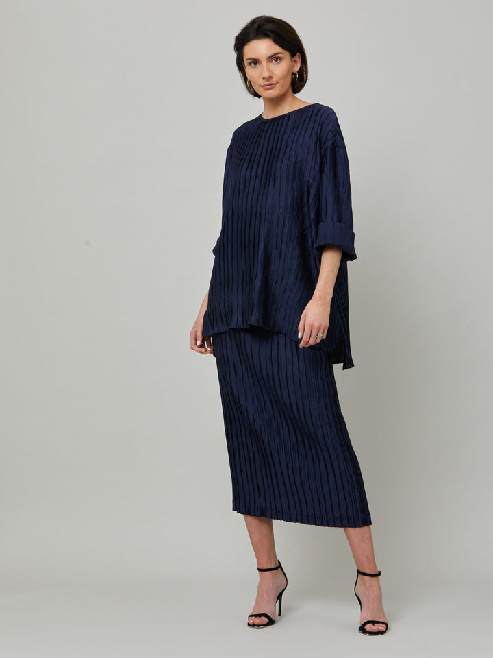 Hallie, elegant tunic in polished navy pleated fabric. A simple wardrobe essential, the perfect foil for the matching Roz navy pleated skirt. Features full-length sleeve, shown here rolled up.